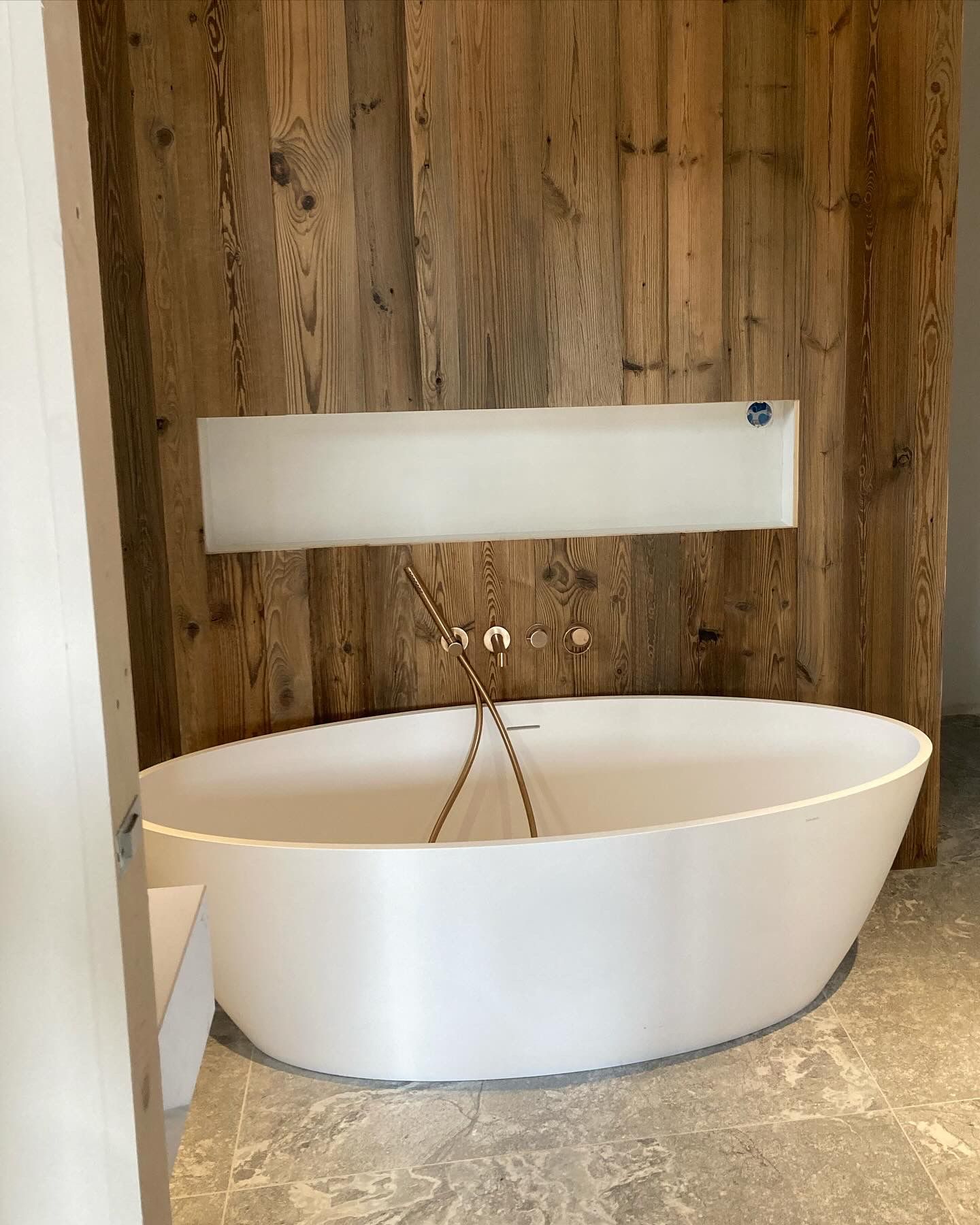 Baignoire îlot sur mur vieux bois